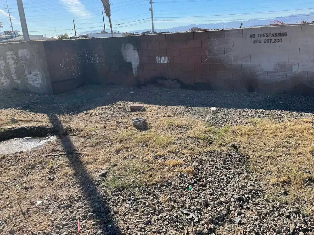 Before: empty dirt lot along a block wall