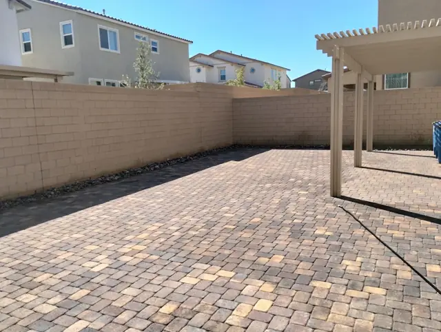 Large backyard paver patio under a pergola