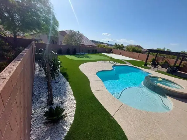 Backyard pool surrounded by artificial turf and desert rock