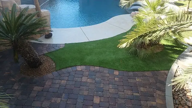 Pool deck with pavers, artificial turf and palm plants
